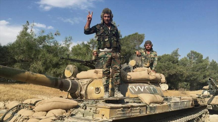 Dos militares sirios a bordo de un tanque hacen la señal de la victoria en las afueras de Hama, en el oeste de Siria.