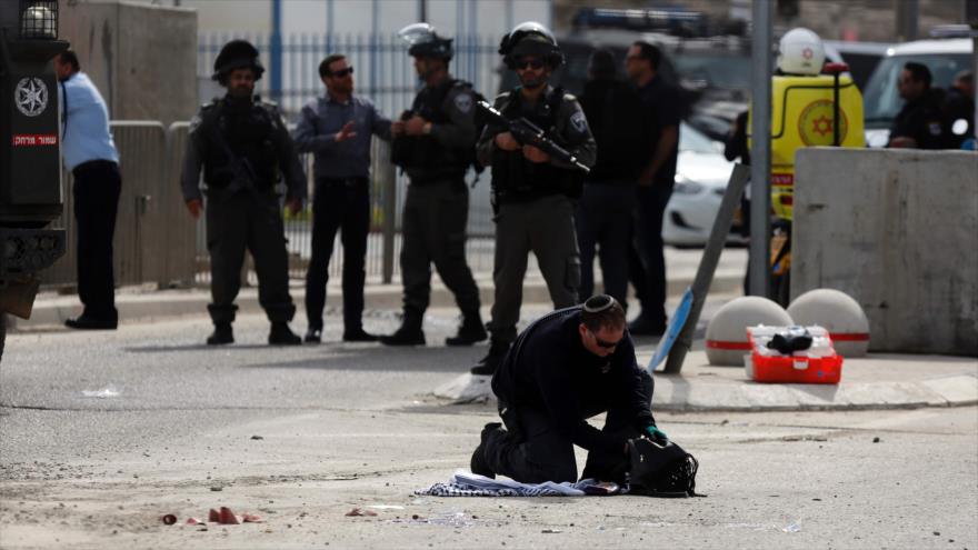 Un policía israelí inspecciona un bolso perteneciente a una mujer, que fue herida de bala por las fuerzas israelíes cerca del puesto de control de Qalandiya, entre Al-Quds y la Cisjordania ocupada, 27 de febrero de 2017.