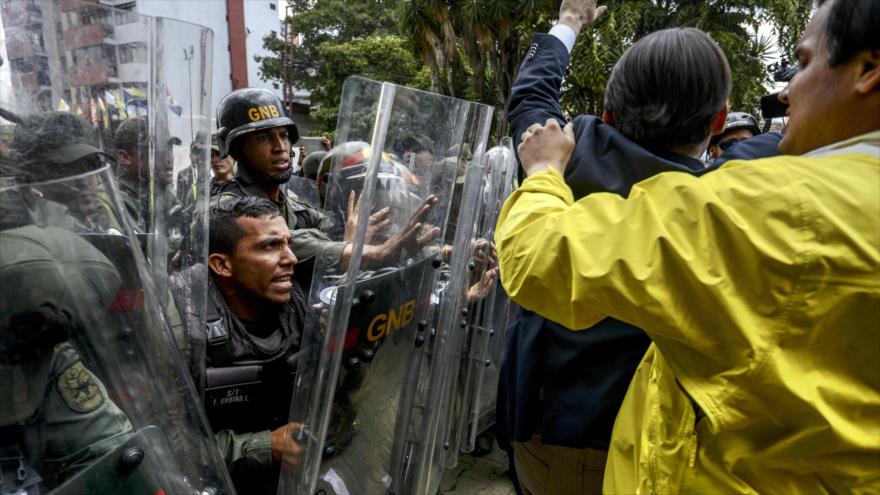 Diputas opositores venezolanos chocan contra la Policía frente el Tribunal Superior de Justicia (TSJ) en Caracas, 30 de marzo de 2017.
