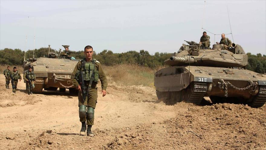 Los soldados israelíes están desplegados cerca a un tanque y un transporte blindado de personal a lo largo de la frontera entre los territorios ocupados y la Franja de Gaza, 4 de mayo de 2016.
