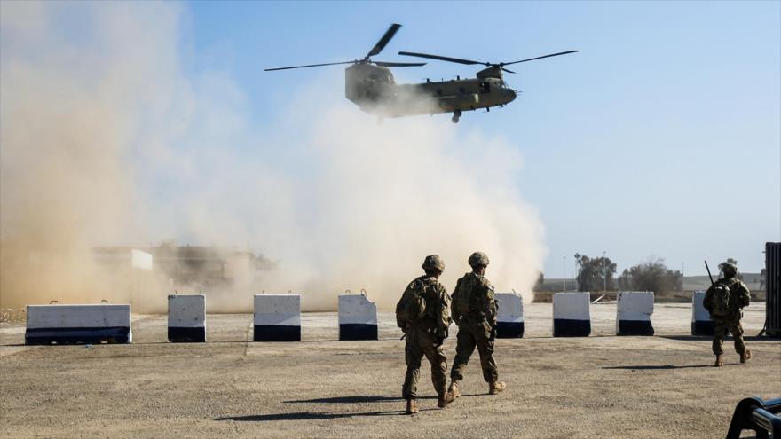 Las tropas estadounidenses caminan mientras que un helicóptero, modelo Boeing CH-47 Chinook de EE.UU., sobrevuele la ciudad de Mosul, norte de Irak, 22 de febrero de 2017.