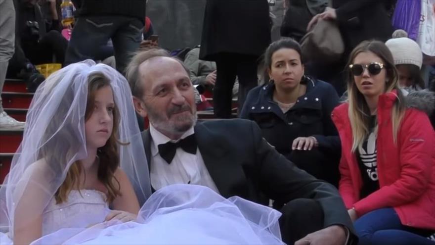 Hombre de 65 años con una niña de 12, simulando una boda en un experimento sobre la reacción social al matrimonio infantil.