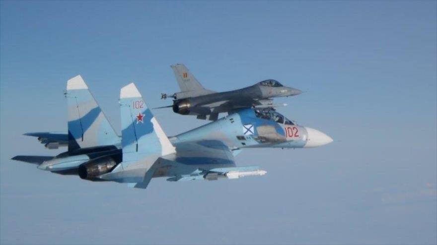 Un avión de combate ruso su-27 (dcha.) escoltado par un caza F-16 de la Fuerza Aérea belga.