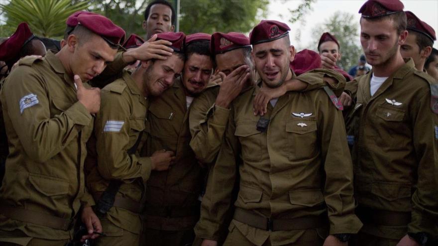 Soldados israelíes lloran durante el funeral de su amigo en un cementerio en los territorios ocupados palestinos.