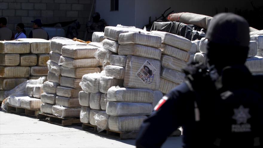 Un policía de México monta guardia junto a paquetes de marihuana presuntamente incautados al Cártel de Sinaloa.