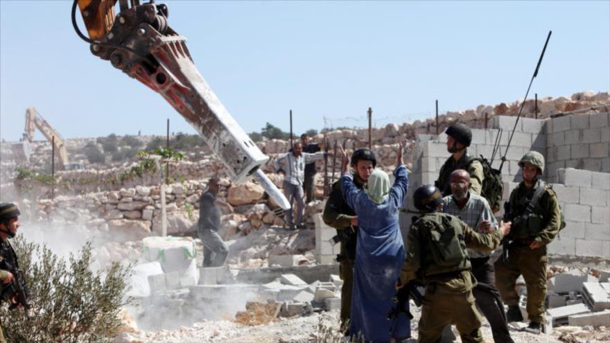 Fuerzas israelíes demuelen una casa palestina frente a sus propietarios en la Cisjordania ocupada.