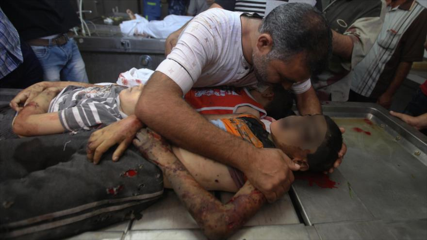 Familiar de tres niños palestinos asesinados por un ataque aéreo israelí visita sus cuerpos en la morgue del hospital Al-Shifa, en la Ciudad de Gaza. 21 de agosto de 2014