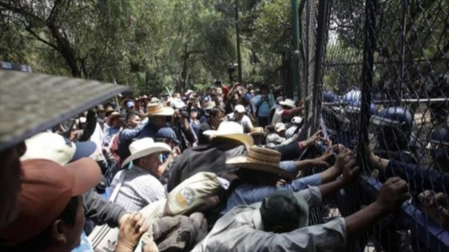 Campesinos mexicanos que marchan hacia Los Pinos intentan tirar vallas dispuestas por granaderos. 19 de marzo de 2015 