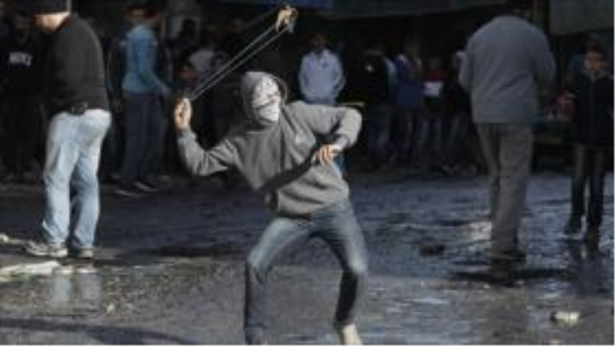 Un palestino lanza piedras contra soldados israelíes