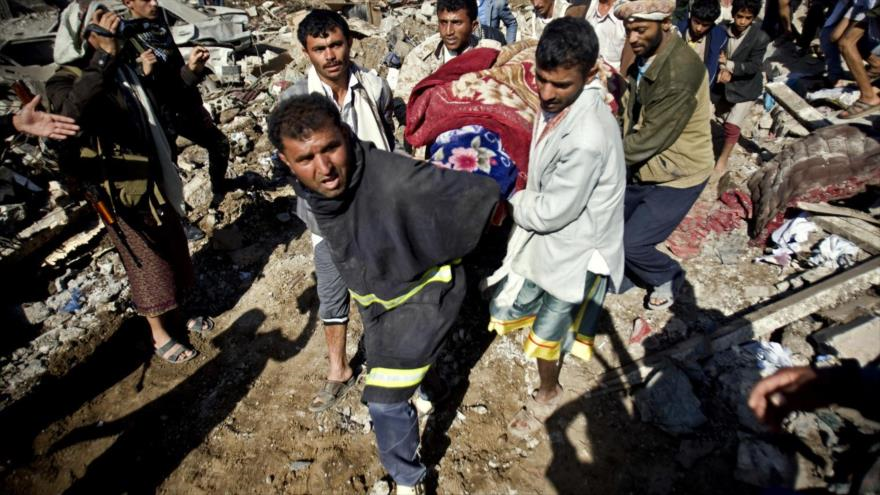 La gente traslada el cuerpo de una víctima extraída de debajo de los escombros de viviendas destruidas en ataques aéreos saudíes en Saná, capital de Yemen