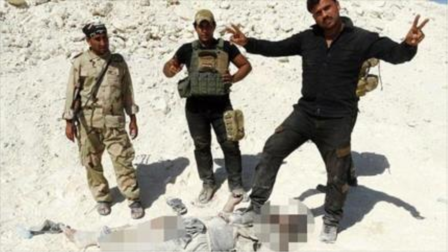 Fuerzas iraquíes posan junto al cadáver de un miembro del EIIL