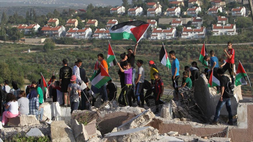 Los palestinos alzan su bandera en el lugar de su casa destruida por las fuerzas israelíes. El 28 de abril de 2015.
