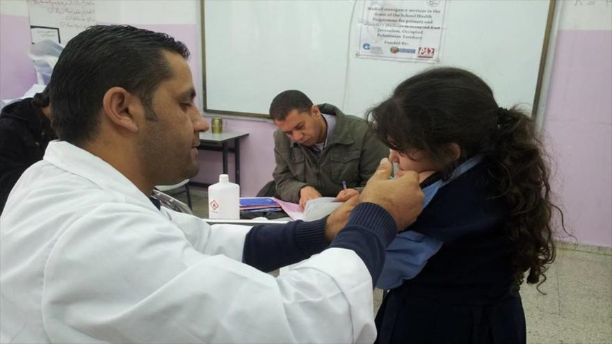 Un médico está llevando a cabo revisiones médicas a una niña palestina.
