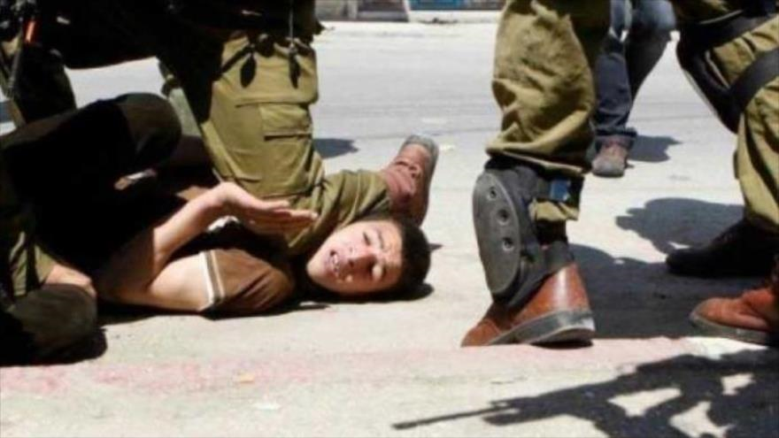 Un soldado israelí pone y fuerza con su pie el cuello de un niño palestino.