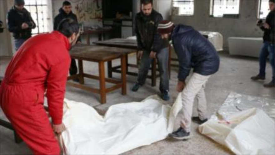 Unos hombres llevan el cuerpo de una fuerza gubernamental en una morgue en la norteña ciudad siria de Alepo