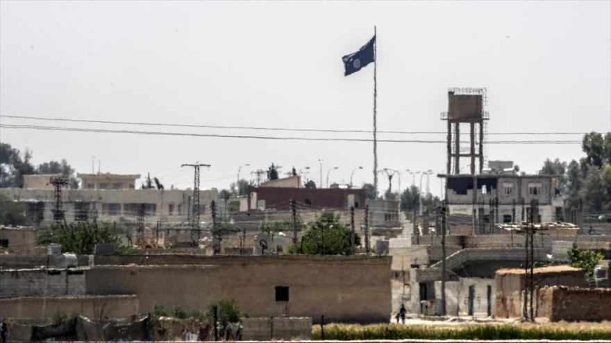 Una foto tomada desde Akçakale, sur de Turquía, en la que se puede ver una bandera del grupo terrorista EIIL (Daesh, en árabe) en el centro de la ciudad siria de Tal Abyad. 13 de junio de 2015