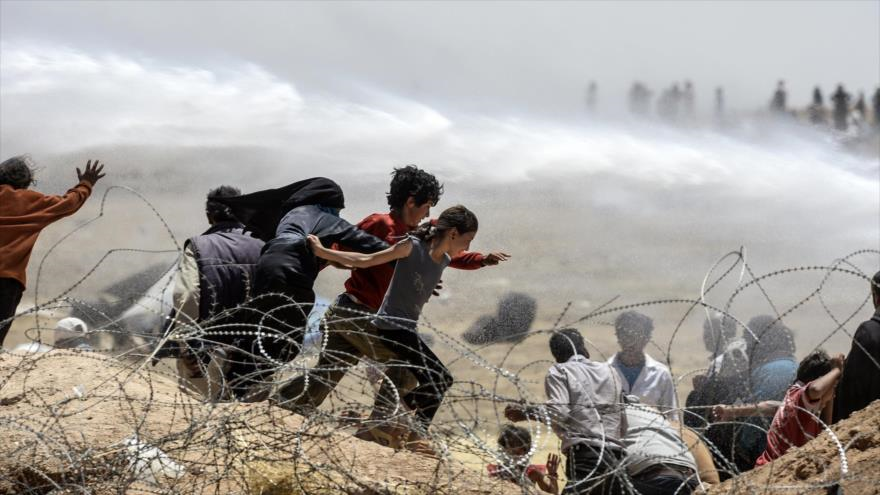 Desplazados sirios escapan mientras las fuerzas fronterizas turcas utilizan cañones de agua para dispersarlos , 13 de junio de 2015.