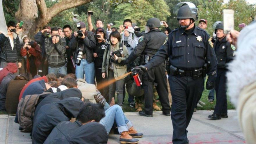 Un policía estadounidense aplica spray de pimienta a manifestantes.