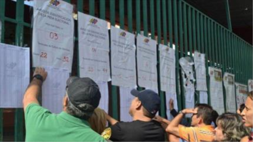 Venezolanos miran la lista de candidatos para votar en los comicios primarios del Partido Socialista Unido de Venezuela (PSUV). 28 de junio de 2015