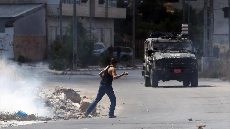 Joven palestino defiende su tierra de la ocupación israelí frente a la prisión militar israelí de Ofer, cerca de la ciudad de Beitunia (centro de Palestina), tras una manifestación contra los asentamientos ilegales israelíes, 12 de junio de 2015.