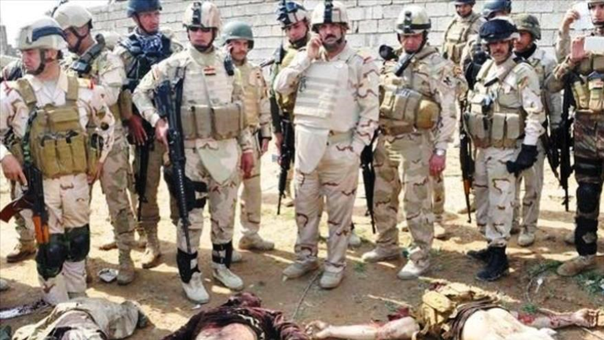 Soldados del Ejército iraquí posan junto a los cueropos sin vida de terroristas del EIIL