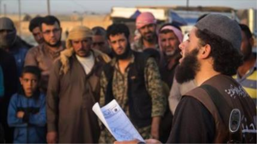 Un miembro de Daesh leyendo las leyes impuestas por esta banda terrorista en regiones bajo su dominio en Siria