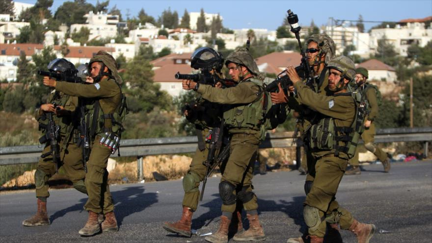Soldados del ejército israelí apuntan sus armas contra los palestinos.