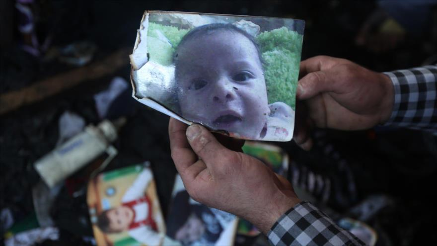 Un hombre muestra la imagen del niño palestino identificado como Ali Saad Daubasha, quien murió carbonizado, el 30 de julio, cuando varios colonos israelíes incendiaron su vivienda en el norte de Cisjordania.