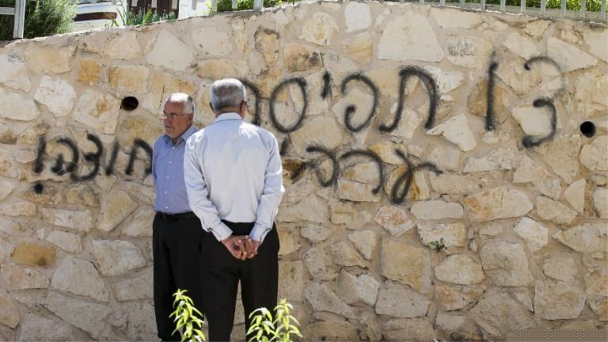 Árabes israelíes frente a una mezquita en la ciudad de Umm al-Faham con la pared pintada con el grafiti "Fuera árabes"