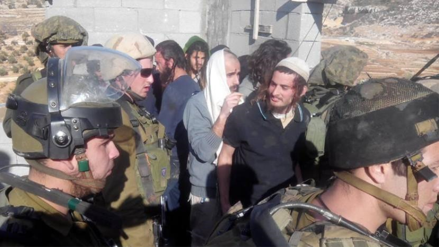 Varios colonos israelíes junto a soldados de este régimen.