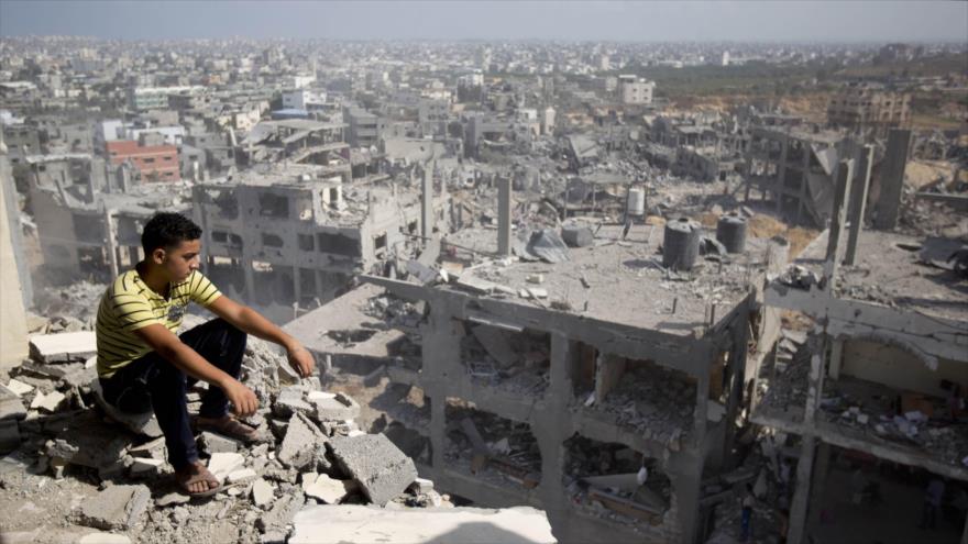 Un palestino sentado entre las ruinas de una vivienda destruida en la última guerra israelí contra Gaza