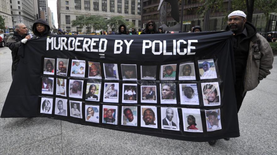Activistas portan una pancarta con las fotos de las víctimas mortales por el accionar de la Policía de EE.UU.