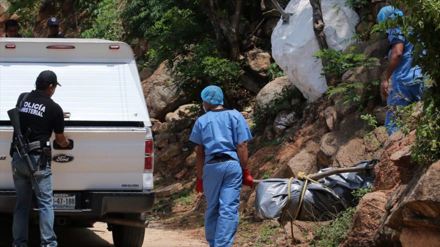 Personal forense traslada a una furgoneta uno de los diez cuerpos encontrados en una fosa común en la ciudad turística de Acapulco, México, 22 de junio 2015.