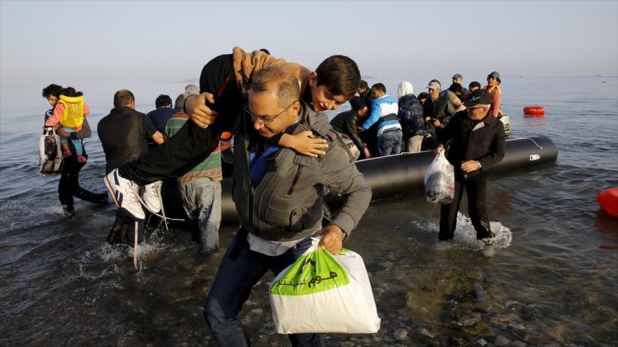 Refugiados sirios en una lancha abarrotada llegando a una isla griega tras cruzar el mar Egeo desde Turquía.