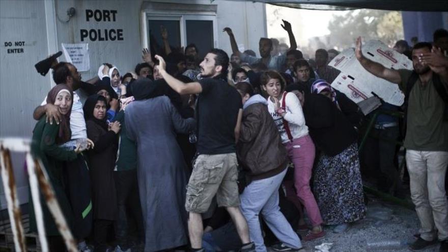 Los refugiados tratan de protegerse de las piedras en una cola de la oficina de registro en el puerto de Mitilene, en la isla griega de Lesbos Egeo, el 6 de septiembre de 2015. 