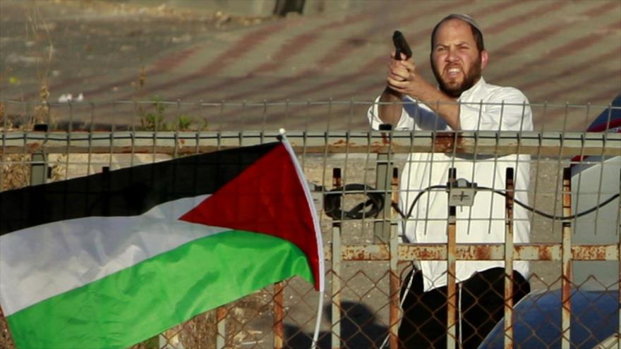Un colono israelí amenaza con arma a manifestantes palestinos.