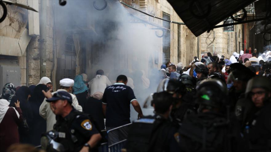 Las fuerzas israelíes montan guardia mientras los palestinos caminan entre el humo de gas lacrimógeno durante los enfrentamientos entre palestinos y los soldados israelíes en el recinto de la Mezquita Al-Aqsa, en Al-Quds (Jerusalén), 13 de septiembre de 2015. 