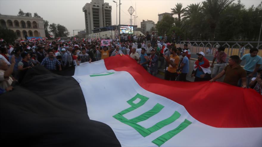 Los iraquíes alzan la bandera del país en la plaza Tahrir en Begdad, capital del país árabe.