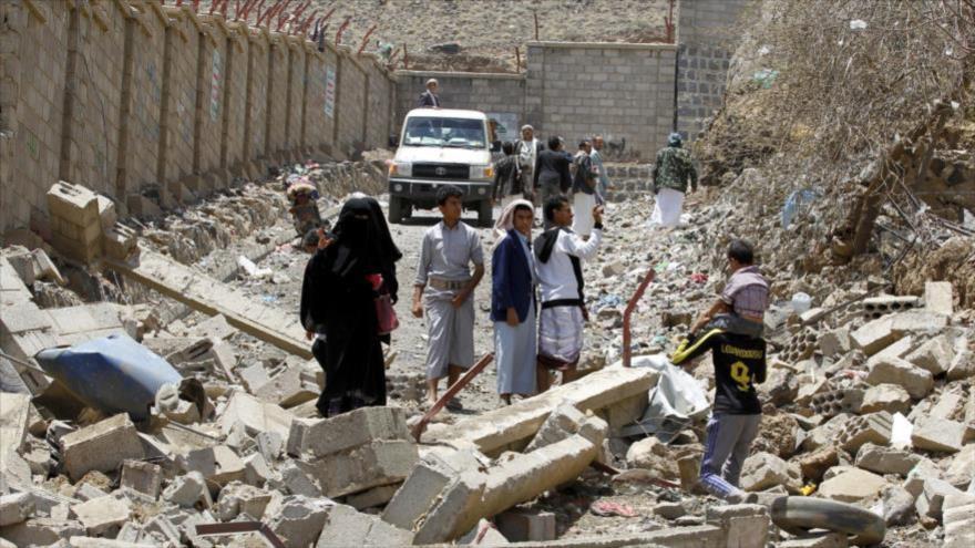 Varios yemeníes caminan entre los escombros de unos edificios destruidos en la capital del país, Saná, a raíz de los ataques aéreos saudíes.