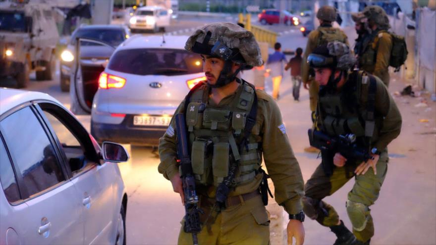Soldados israelíes inspeccionan coches en un puesto de control en la ocupada Cisjordania