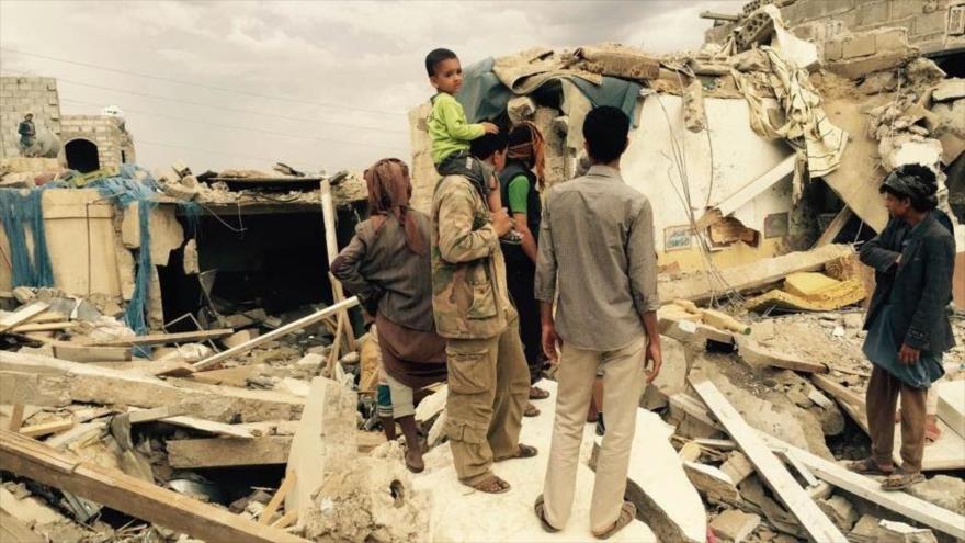 Civiles yemeníes en medio de los escombros de un edificio afectado por los bombardeos saudíes contra Yemen