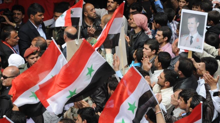 Seguidores del presidente sirio, Bashar al-Asad, llevan imágenes del presidente y hondean la bandera nacional de su país.