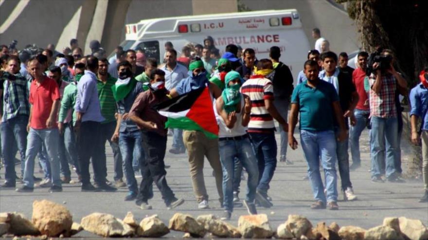 Manifestantes palestinos lanzan piedras contra efectivos israelíes durante una marcha en Ramalá.