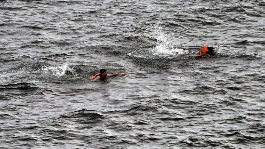 Dos refugiados tratan de llegar a nado a la isla griega de Lesbos, tras hundirse su embarcación en el mar Egeo.