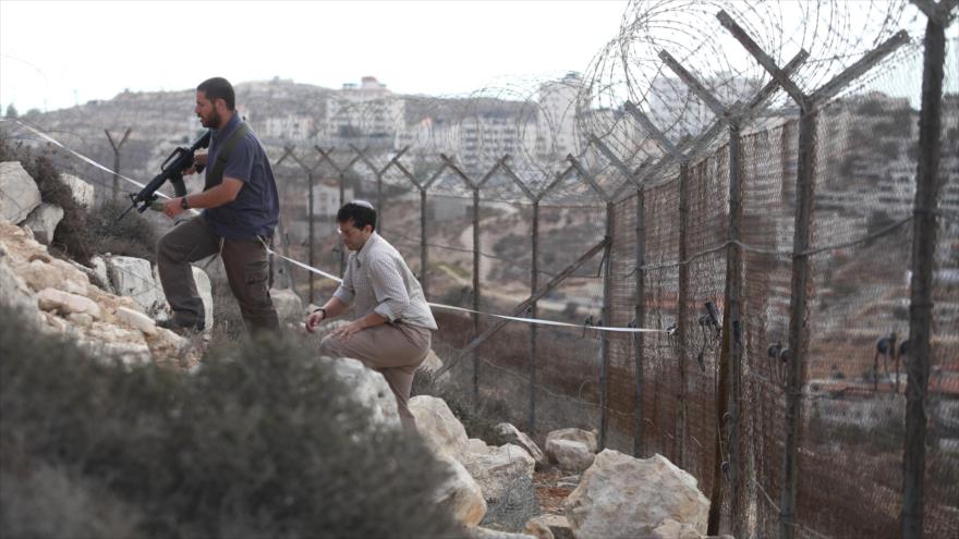 Colonos armados israelíes revisan una localidad en Cisjordania.