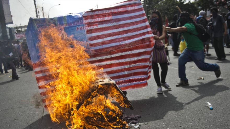 Peruanos queman la bandera de EE.UU. en una protesta contra la reunión anual del Fondo Monetario Internacional (FMI) y el Banco Mundial celebrada en Lima (capital). 9 de octubre de 2015