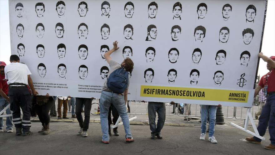 Estudiantes colocan un cartel en la Ciudad de México con las imágenes de los 43 normalistas desaparecidos en Iguala, 23 de septiembre de 2015.