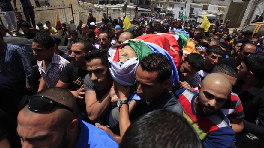 Palestinos celebran ceremonia fúnebre de un palestino muerto por disparos realizados por soldados israelíes en Al-Quds (Jerusalén).