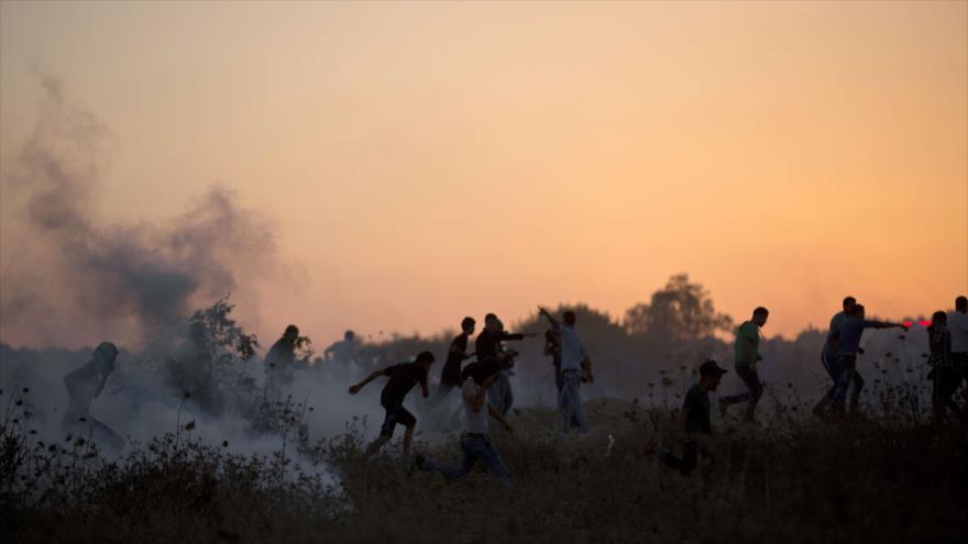 Manifestantes palestinos huyen de humos provocado por gases lacrimógenos disparados por sodlados israelíes en el campo de refugiados de Al-Bureij, ubicado en el centro de Gaza.