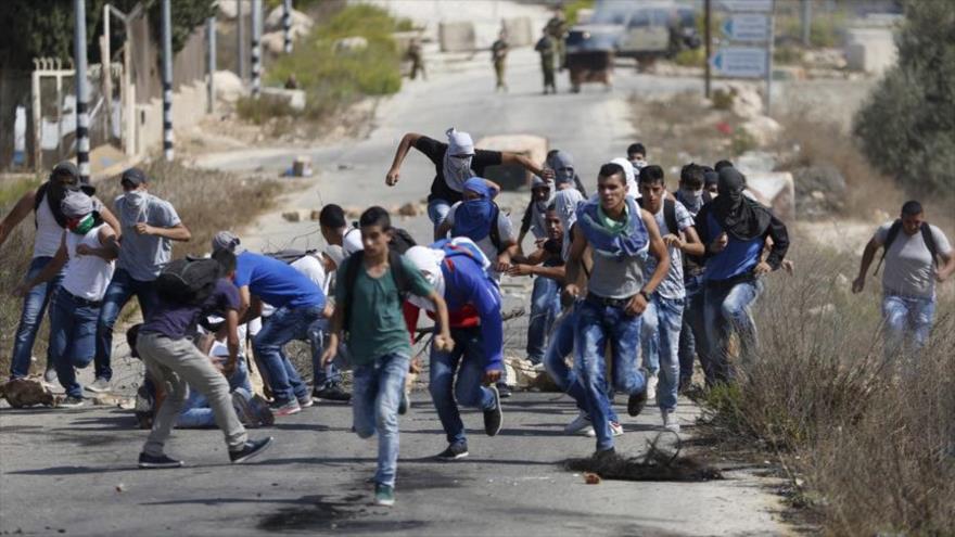 Manifestantes palestinos corren durante los choques con militares israelíes cerca del asentamiento de Beit El, en la ciudad cisjordana de Ramalá.